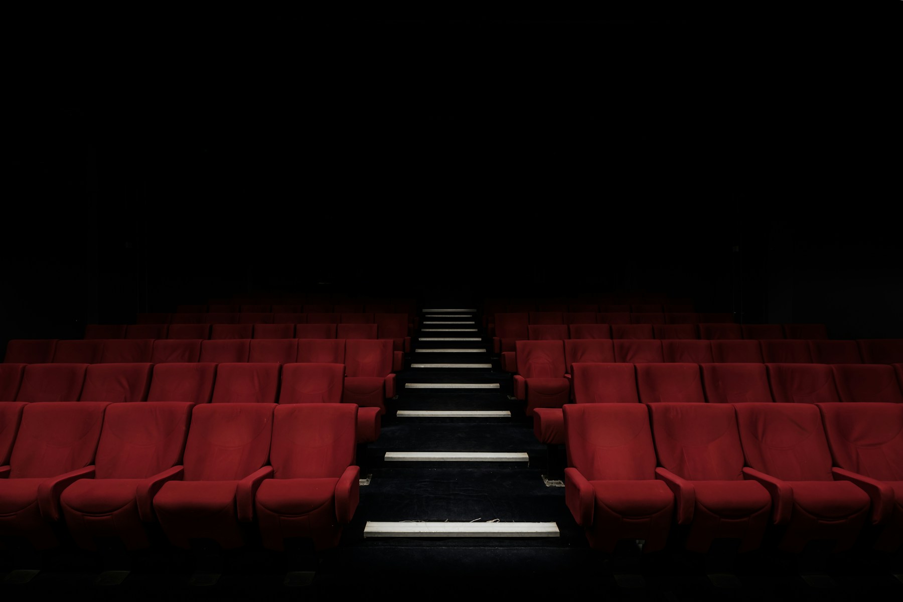 Rows of red cinema seats under theatrical lighting